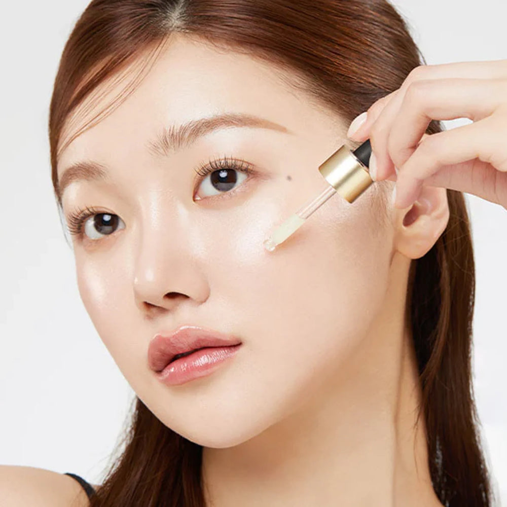Woman applying concealer with a brush to her face on a white background AGE-R-skincare2