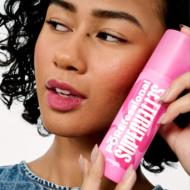 Woman holding a pink bottle labeled 'Supernaturals' with a white background,Benefit The POREfessional Super Setter Setting Spray