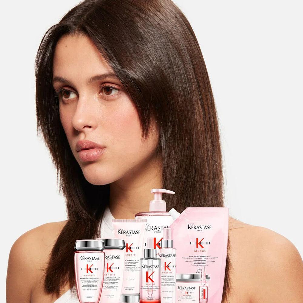 Woman with long brown hair holding Kérastase hair care products on a white background