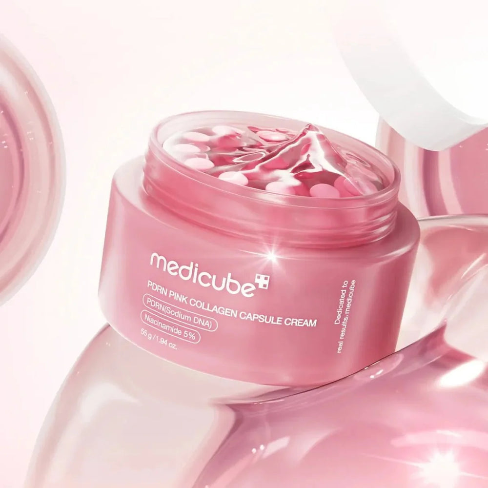 Medicube Form Pink Collagen Capsule Cream in a translucent pink jar with the lid off, showing pink capsule beads inside, set against a glossy pink reflective background.