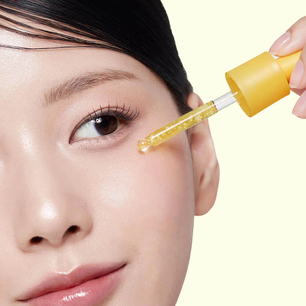 Person applying a Medicube Kojic Acid Turmeric Niacinamide Serum to their eye with a dropper.