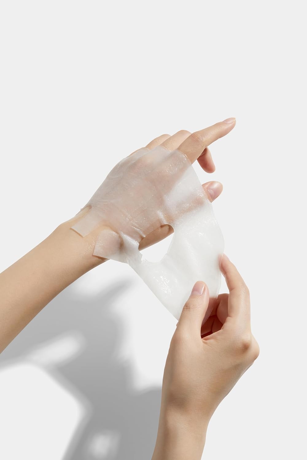 medicube-facemask Person wearing a transparent glove on one hand against a white background