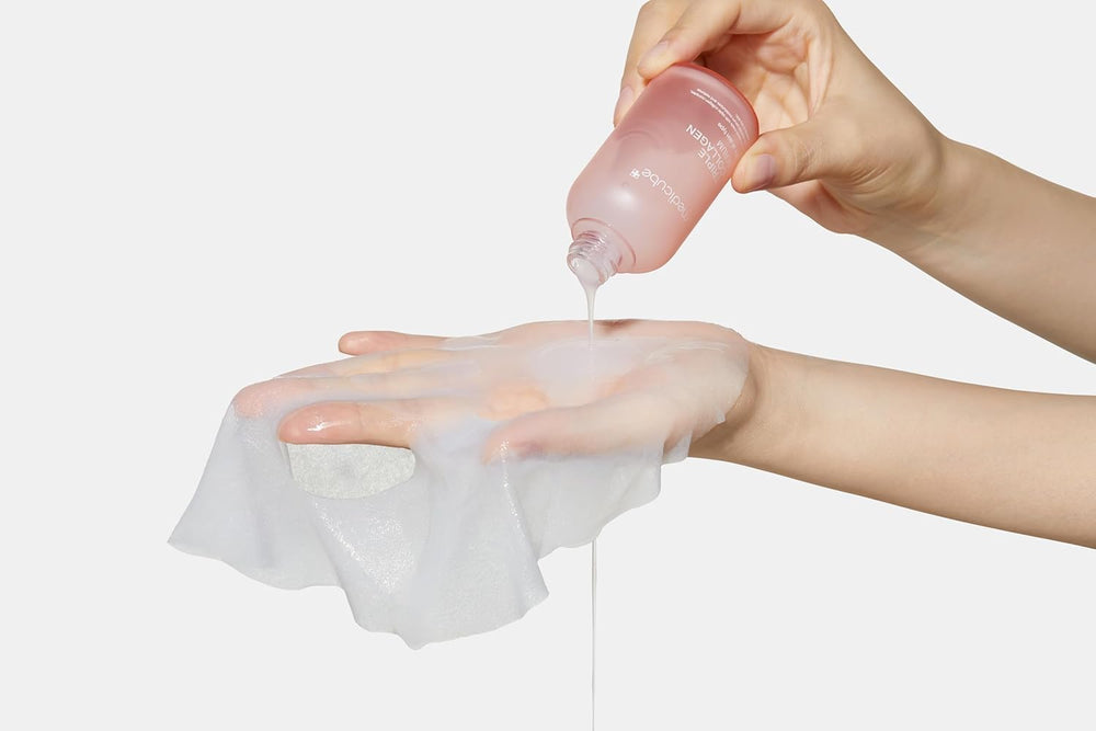  Person applying medicube-facemask a clear gel-like substance to a white cloth with a pink bottle.