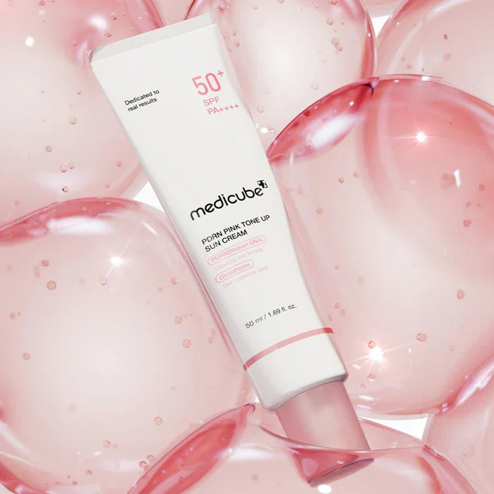 Medicube pink-tone lip sun cream tube surrounded by pink lip gloss on a light pink background
